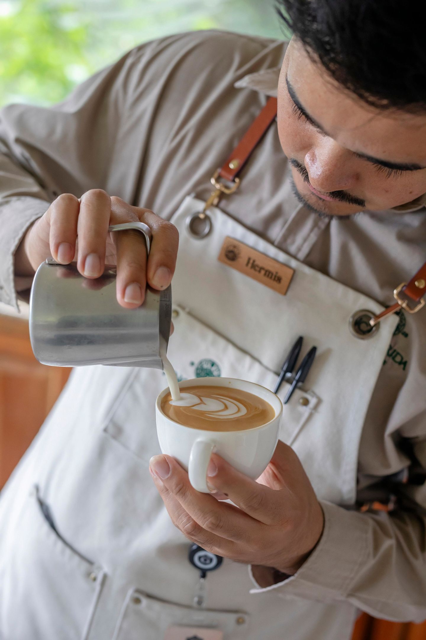 Una persona versa latte in una tazza di caffè.