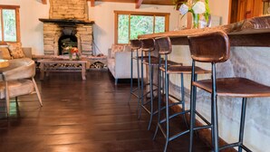 A rustic interior with a stone fireplace, wooden floors, and a bar area with stools. - Hotel Finca Lerida (Los Naranjos)