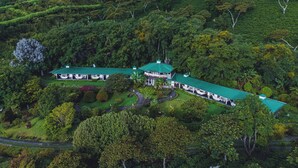 An aerial view of a large, two-story building with a green roof, surrounded by lush greenery and terraced fields. - Hotel Finca Lerida (Los Naranjos)