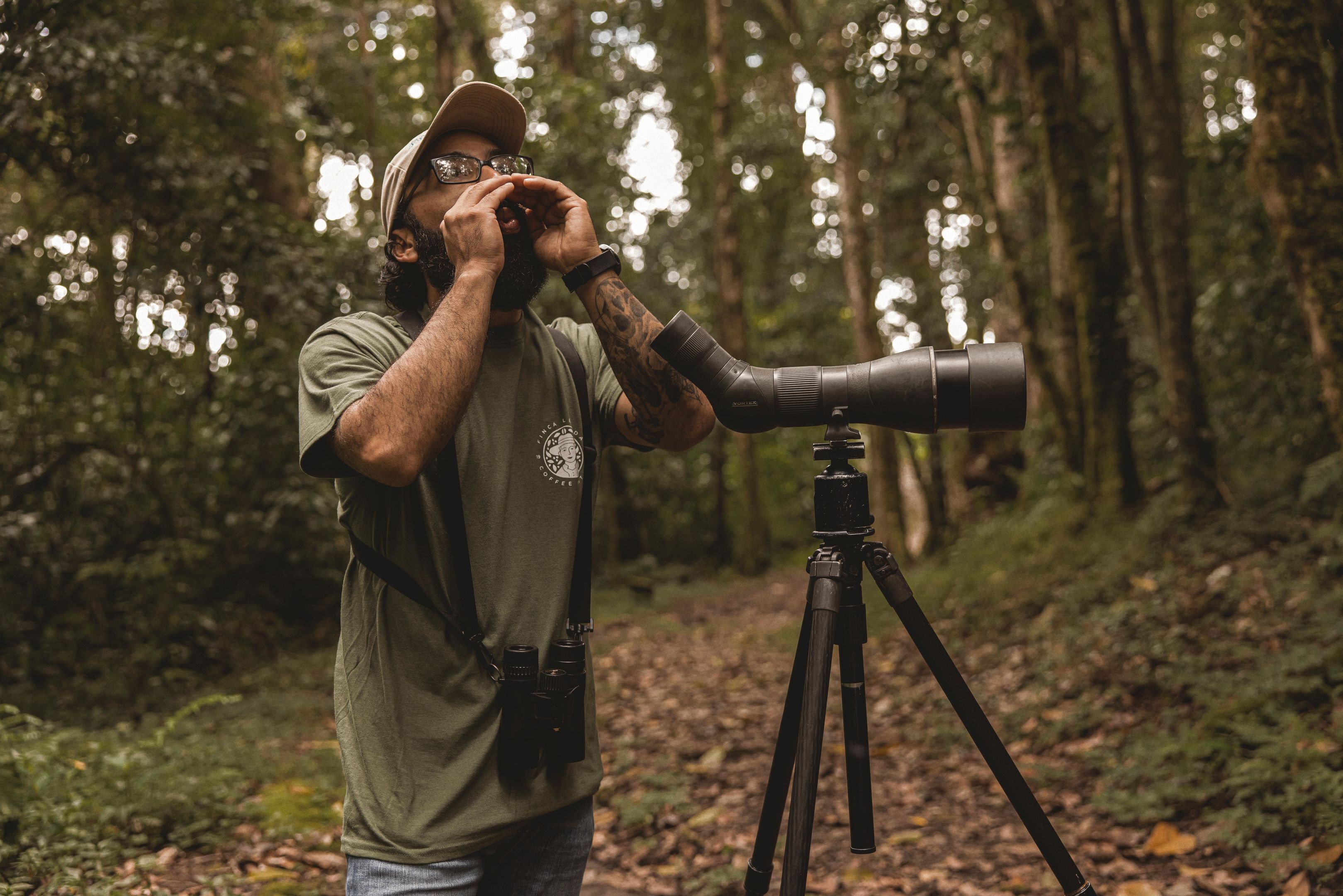 A person using a telescope in a forested area.
