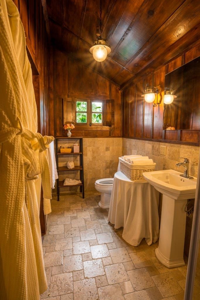 A wooden-paneled bathroom with a white sink, a toilet, and a shelf with towels.