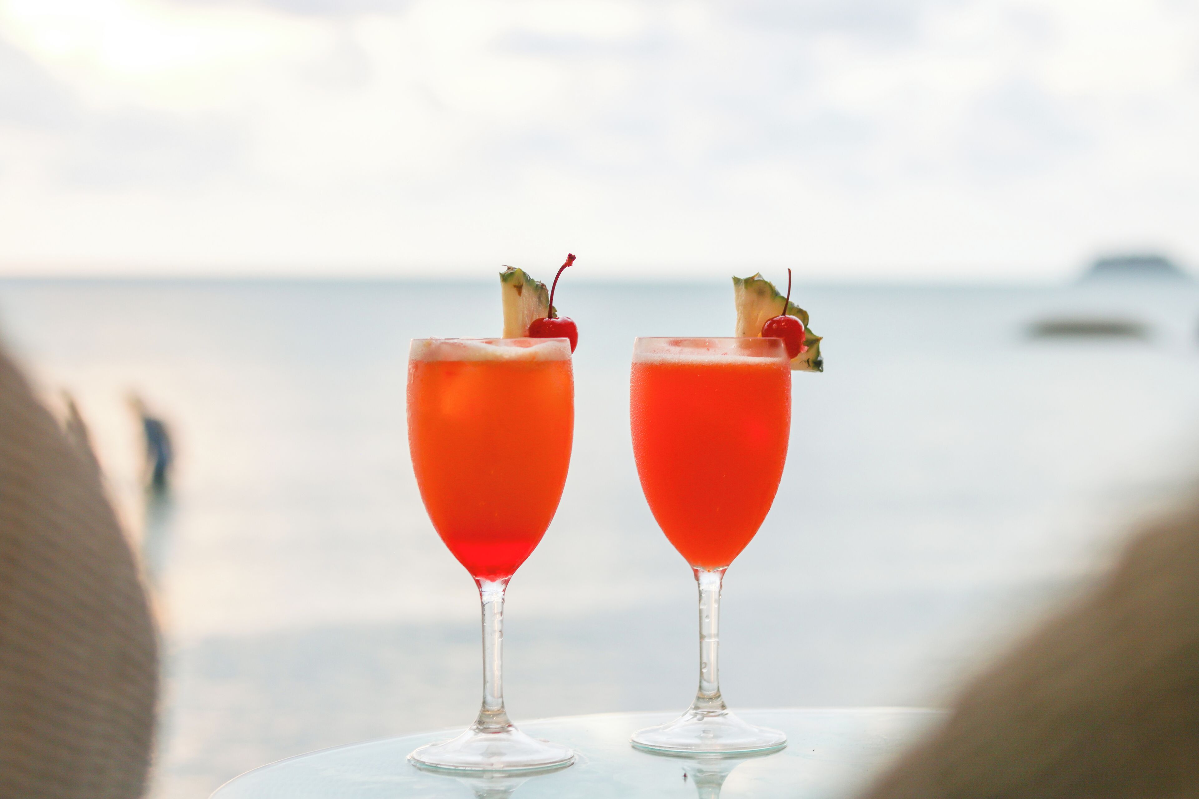 Two cocktails on a table with a view of the ocean.