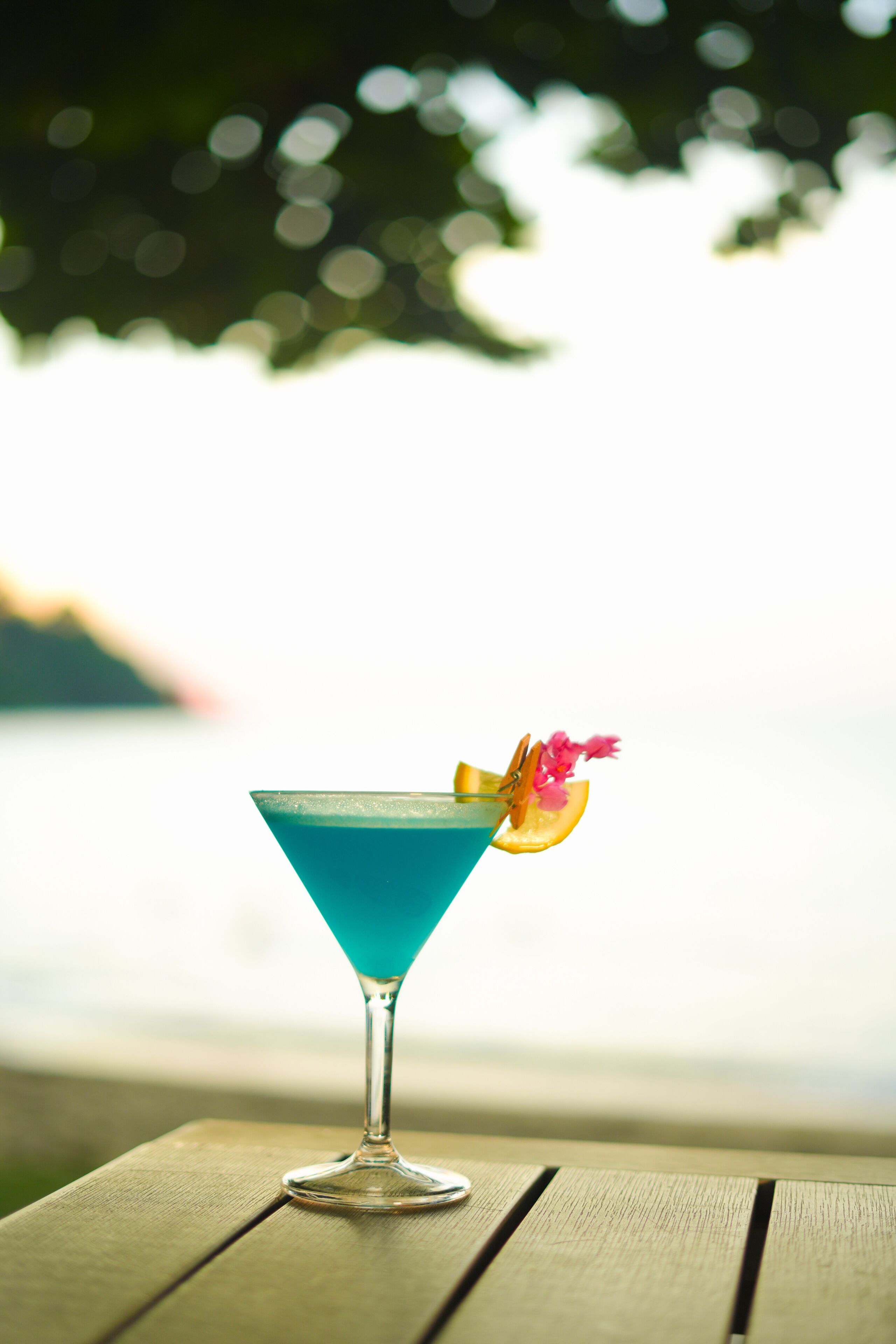 Ein Cocktail im Martiniglas mit einer Garnitur auf einem Holztisch.
