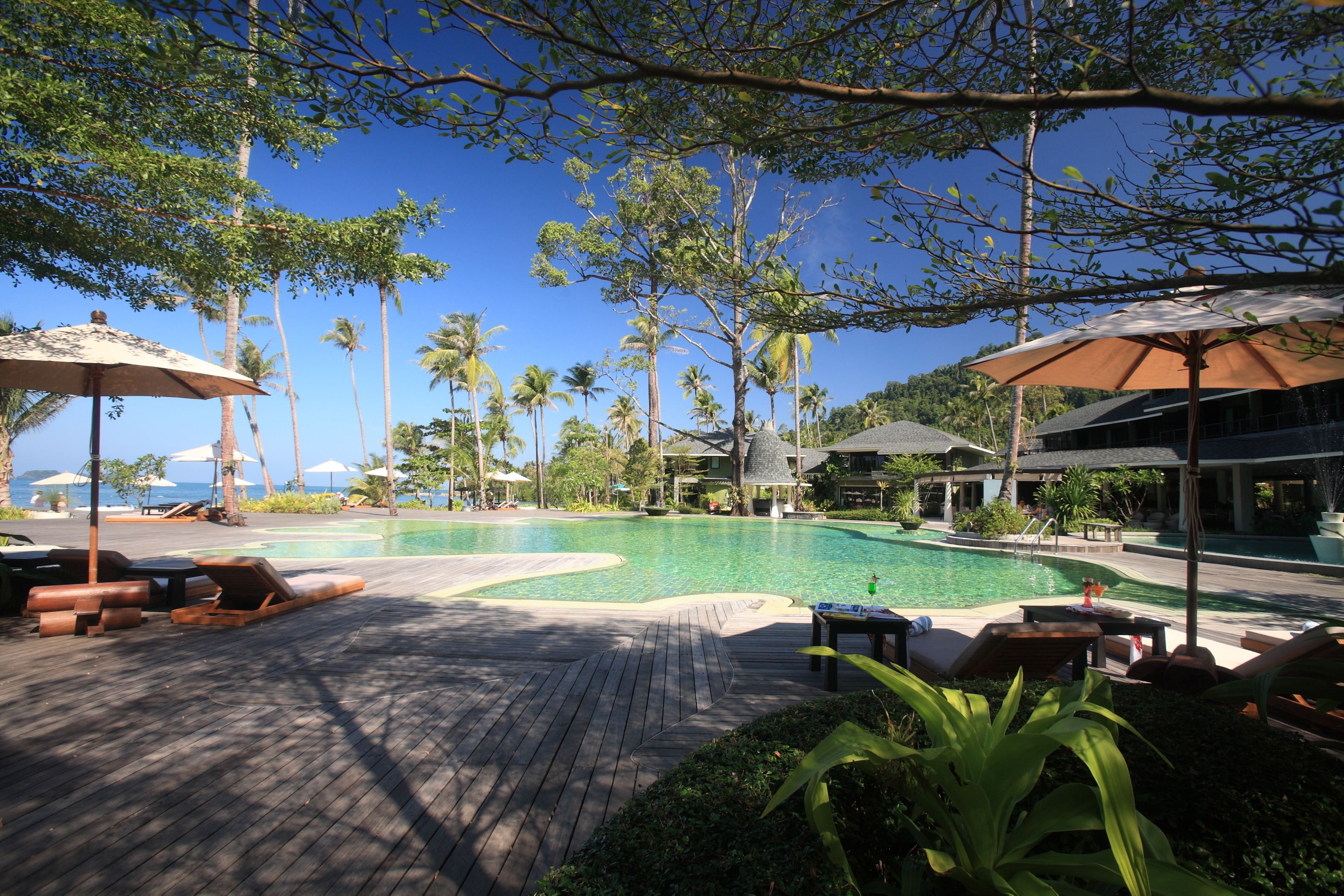 A poolside area with lounge chairs, umbrellas, and a wooden deck.
