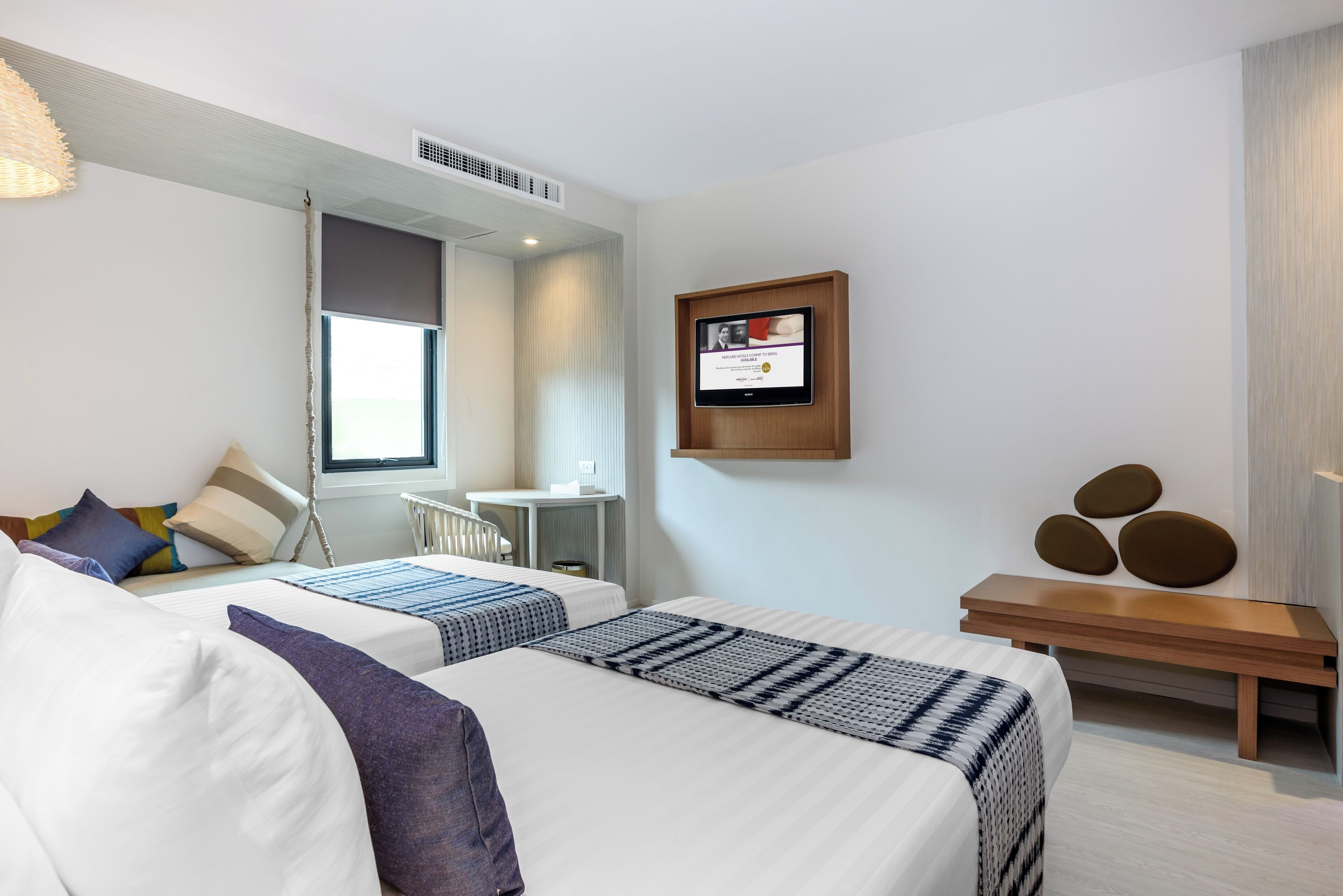 Habitación de hotel con dos camas, un escritorio pequeño, una silla, un televisor y un certificado colgado en la pared.