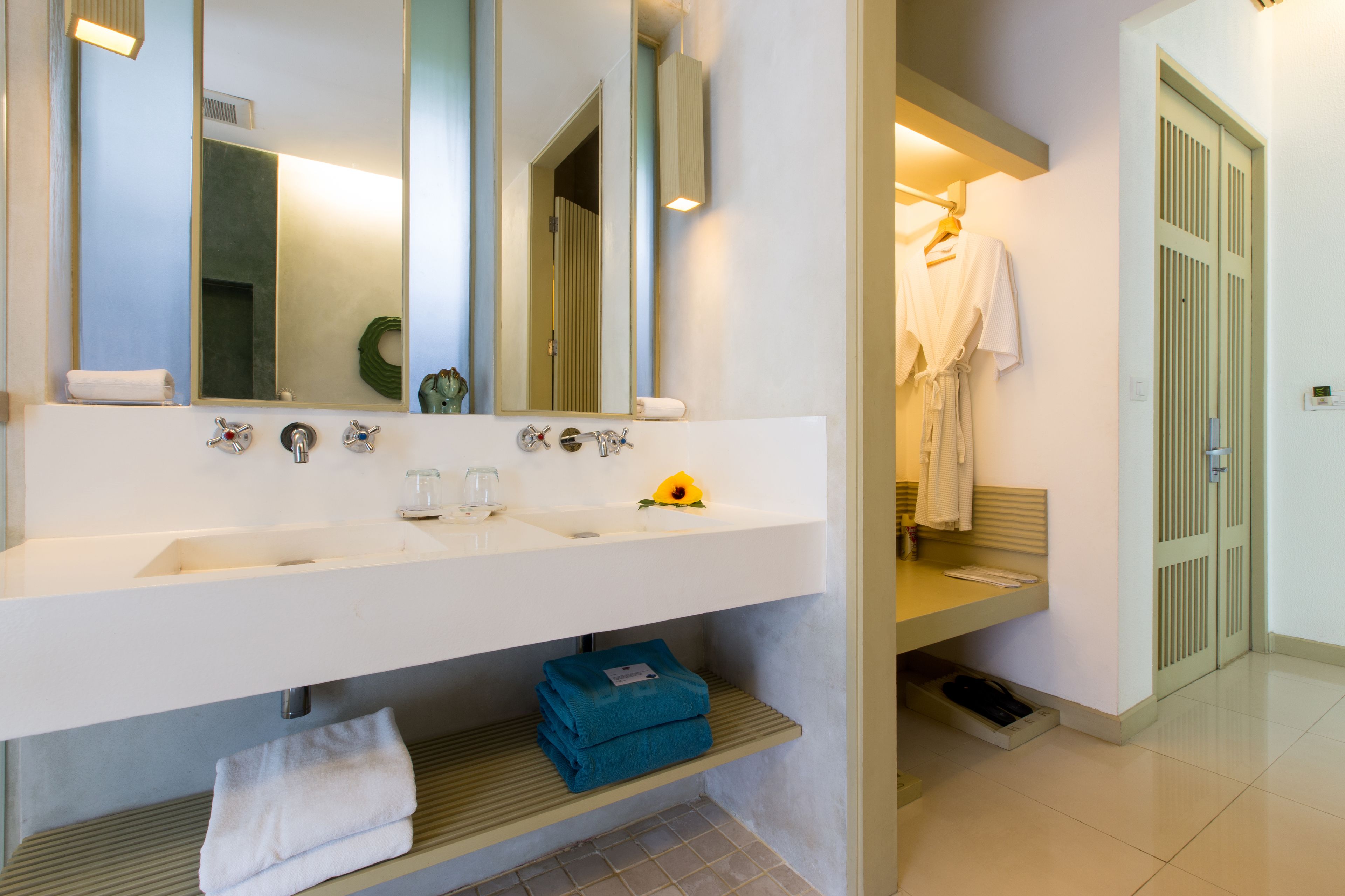 A modern bathroom with a white sink, two faucets, a mirror, and a towel rack.