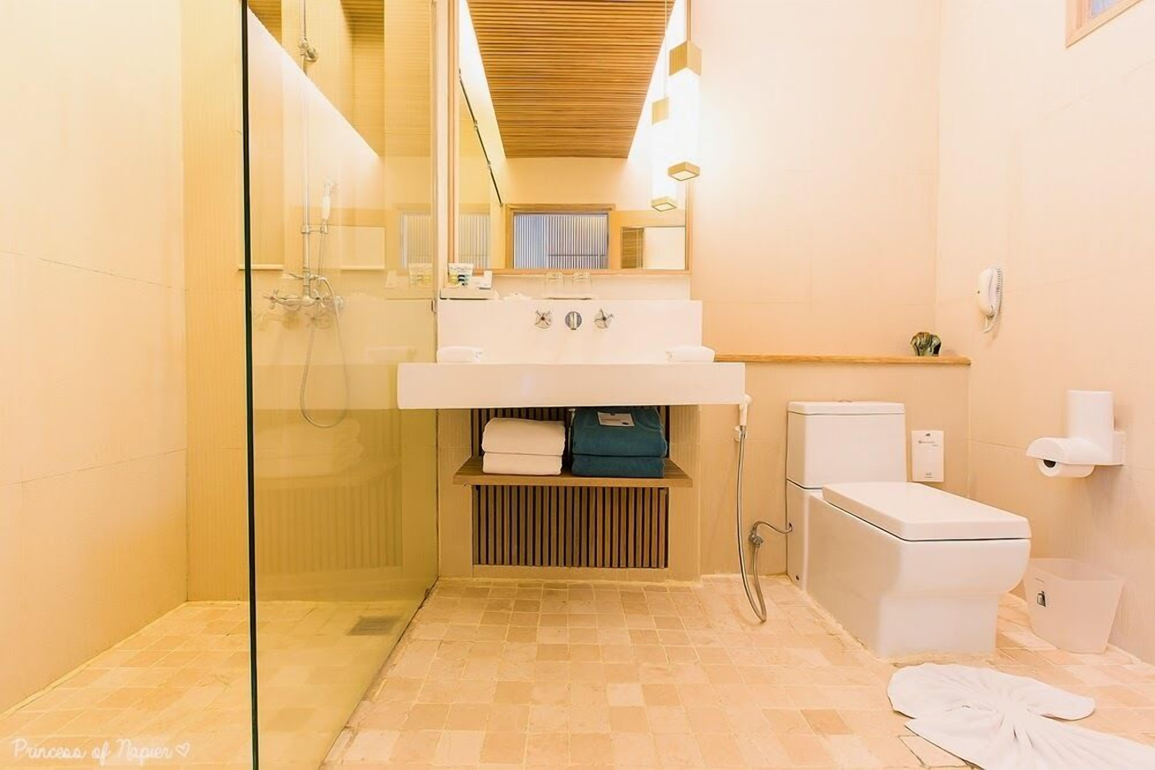 A modern bathroom with a glass-enclosed shower, a white sink, and a toilet.