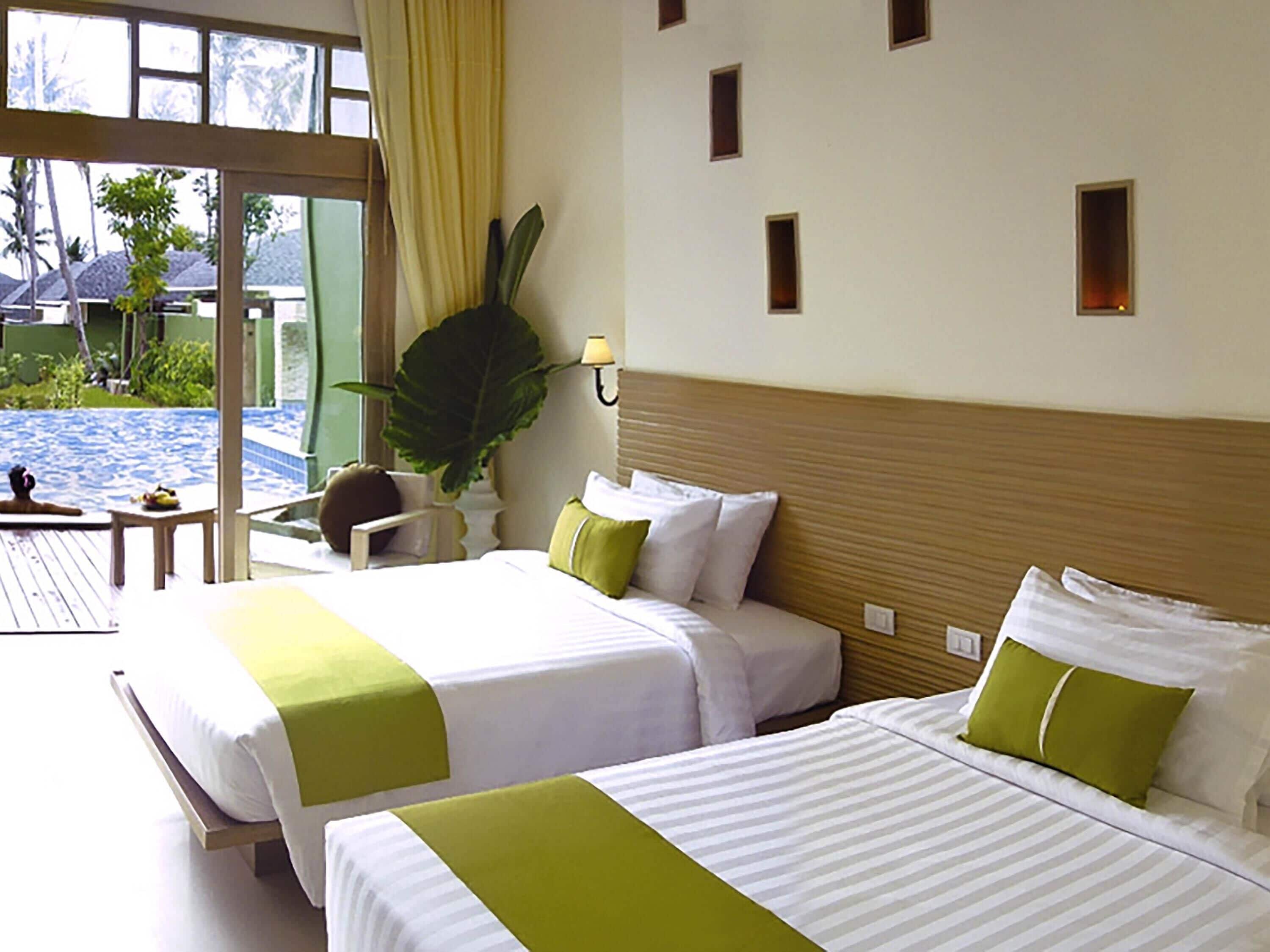 A hotel room with two beds, a large window, a view of a pool, and a plant.