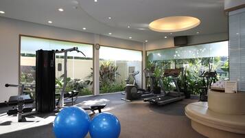 A gym with exercise equipment, large blue exercise balls, and a view of greenery outside.