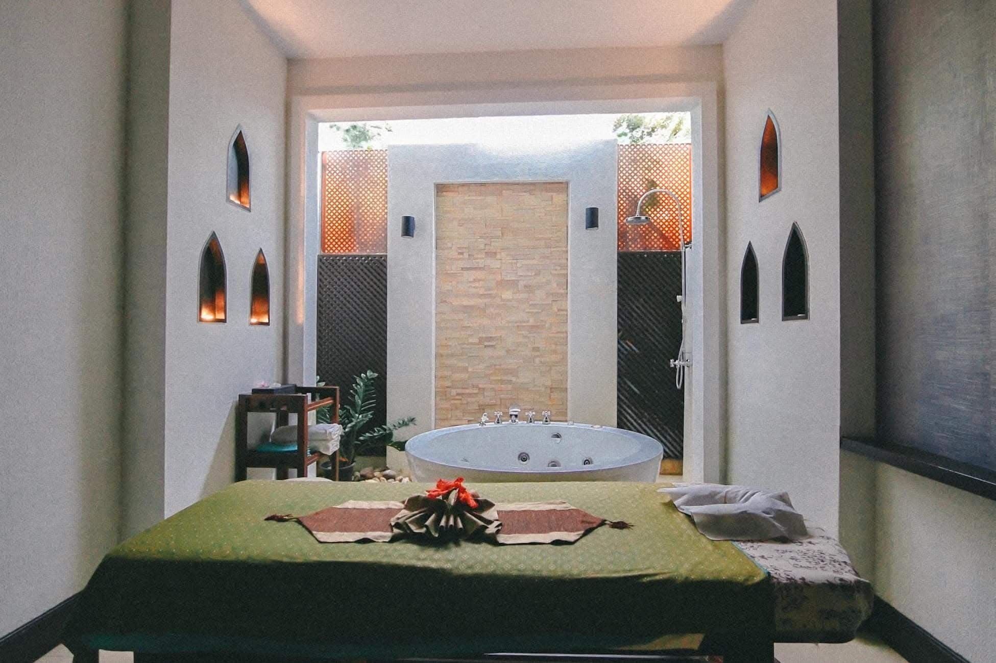 Un cuarto de spa con una camilla de masaje, una bañera y un ventanal con vistas al exterior.