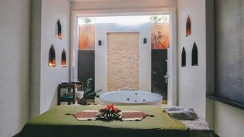Un cuarto de spa con una camilla de masaje, una bañera y un ventanal con vistas al exterior.