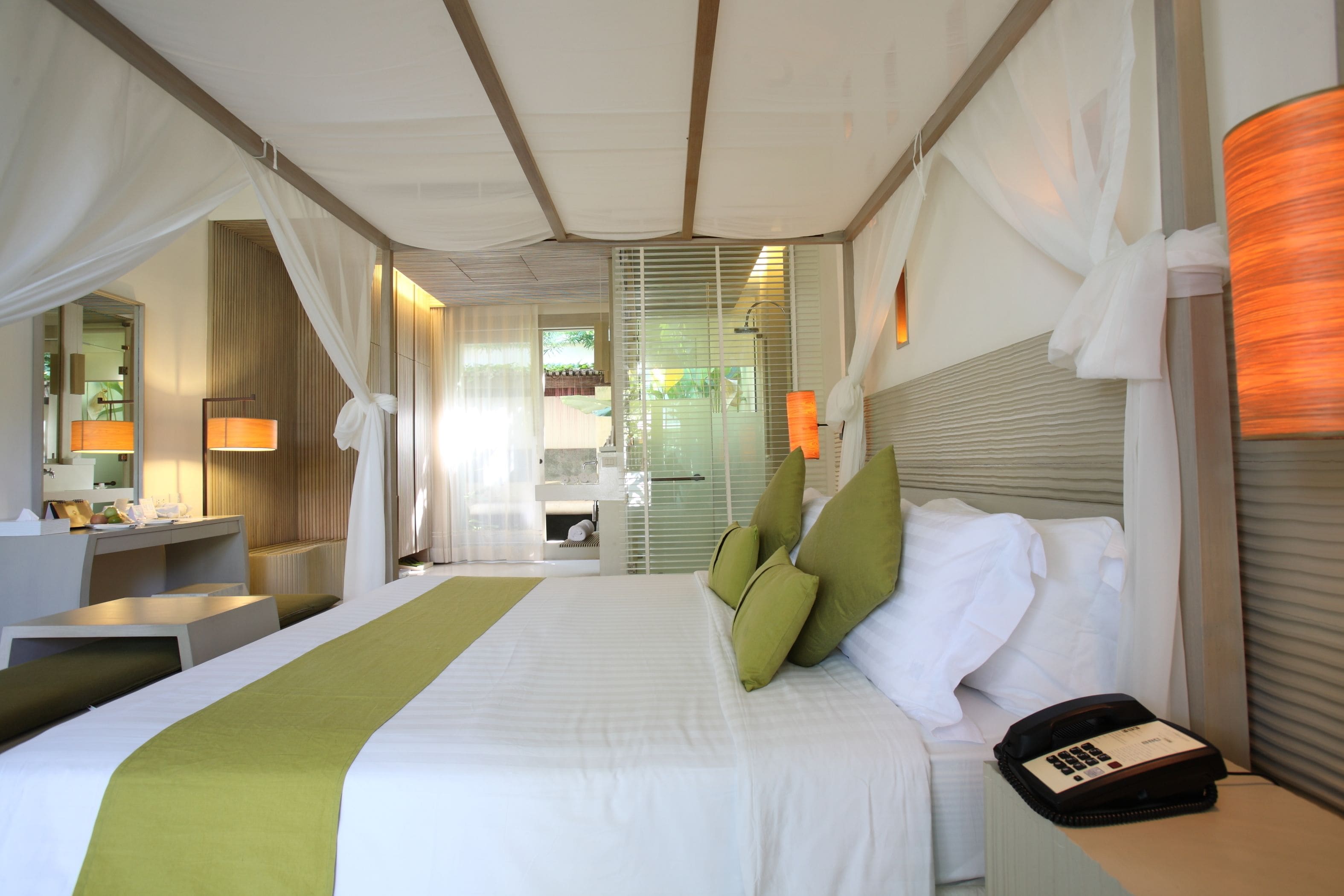Una camera d'albergo con un letto grande, un comodino, una lampada e un telefono.