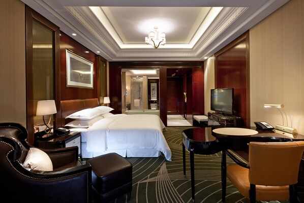Habitación de hotel con una cama grande, un escritorio con una silla, televisión y un baño a la vista.