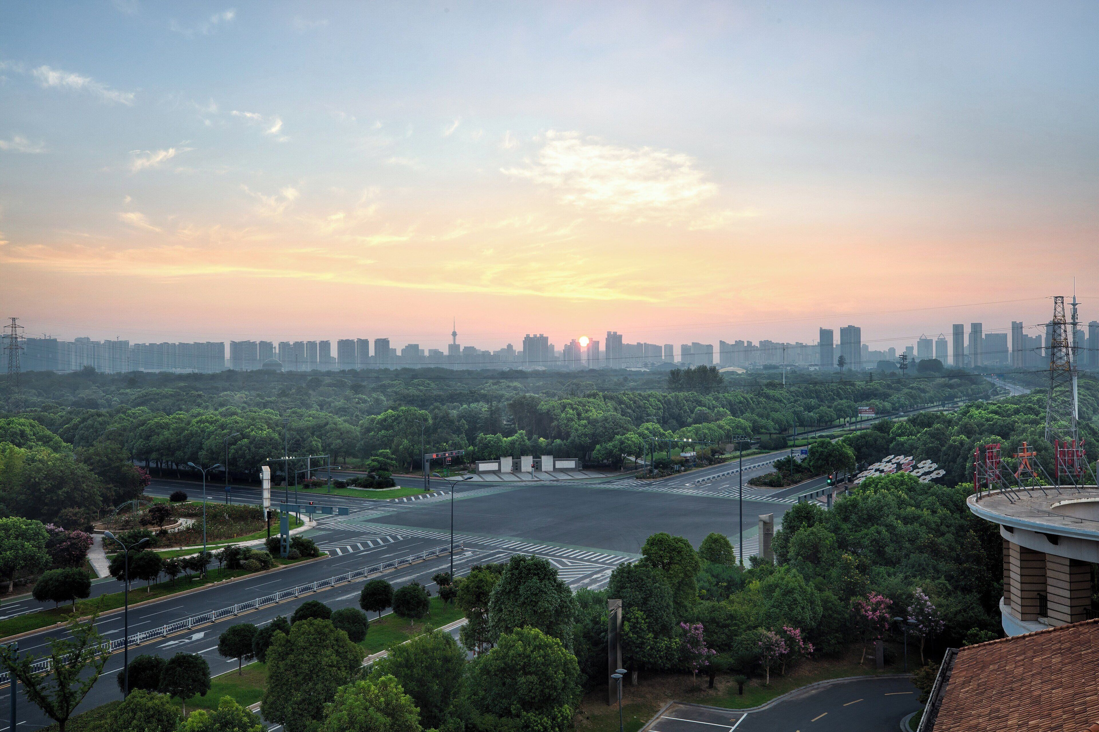 A cityscape with a sunset, a large green park, and a modern building with a dome.