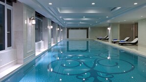 A long indoor swimming pool with clear blue water, surrounded by walls with windows and a ceiling with recessed lighting. - Sheraton Changzhou Wujin Hotel (Changzhou)