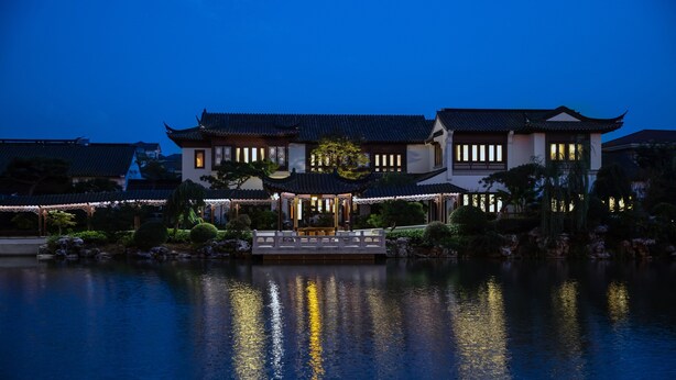 A traditional building with a reflection in the water, surrounded by greenery. - Sheraton Changzhou Wujin Hotel (Changzhou)