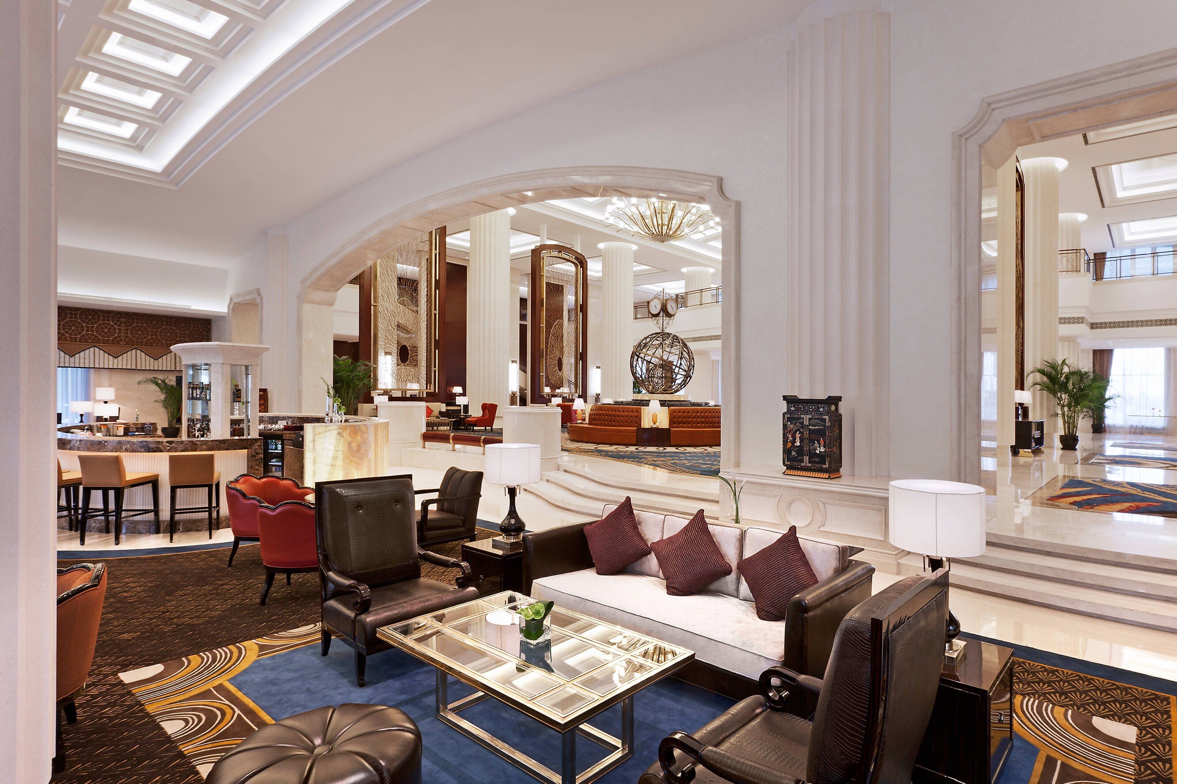 A spacious lobby with a central seating area, a bar, and a reception desk.