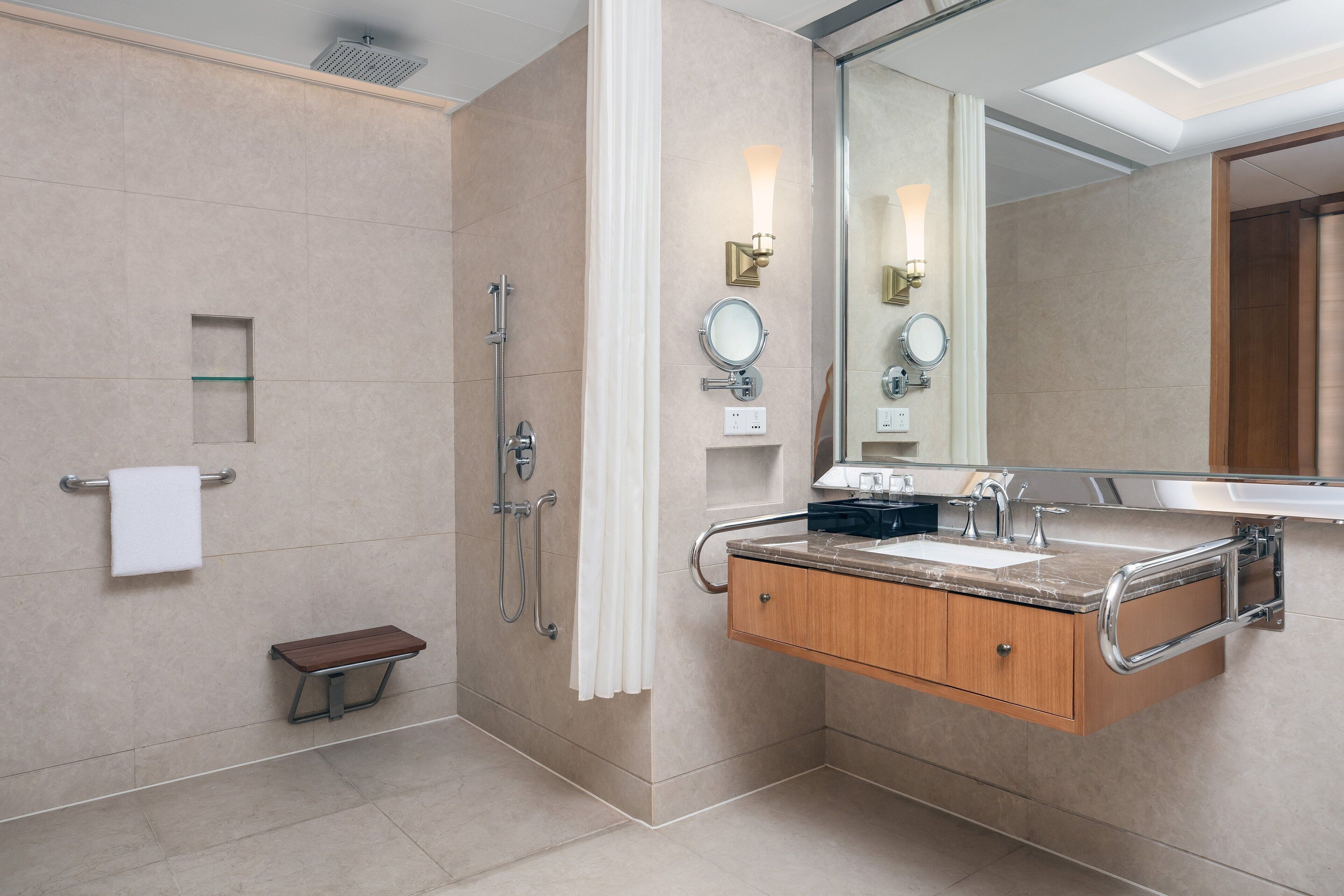 Un baño moderno con ducha, tocador y espejo grande.