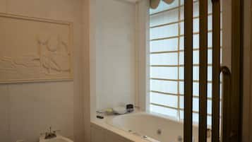 Un baño con bañera, lavamanos y ventana con persianas.