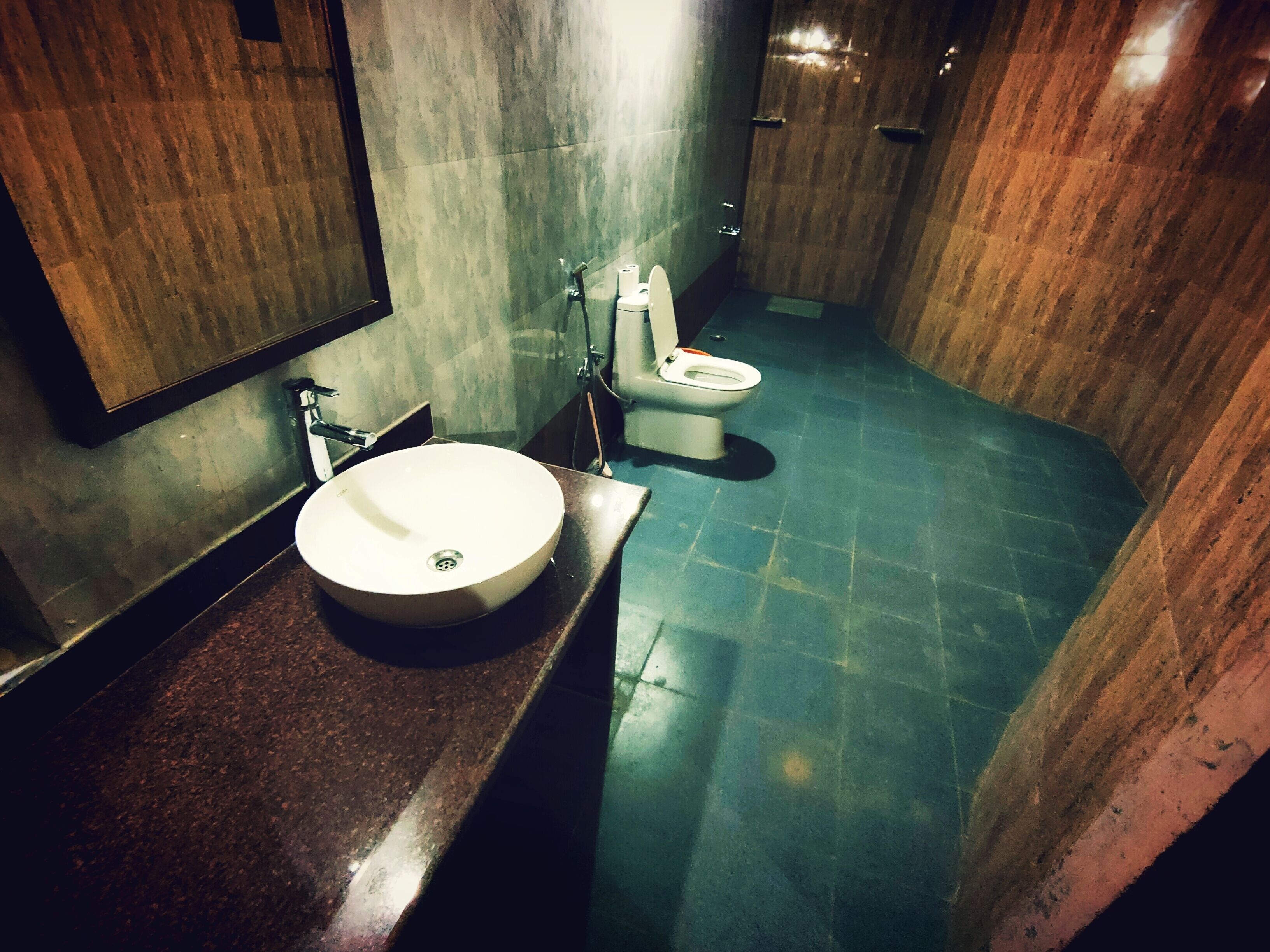 Et badeværelse med en rund håndvask, toilet og et spejl.