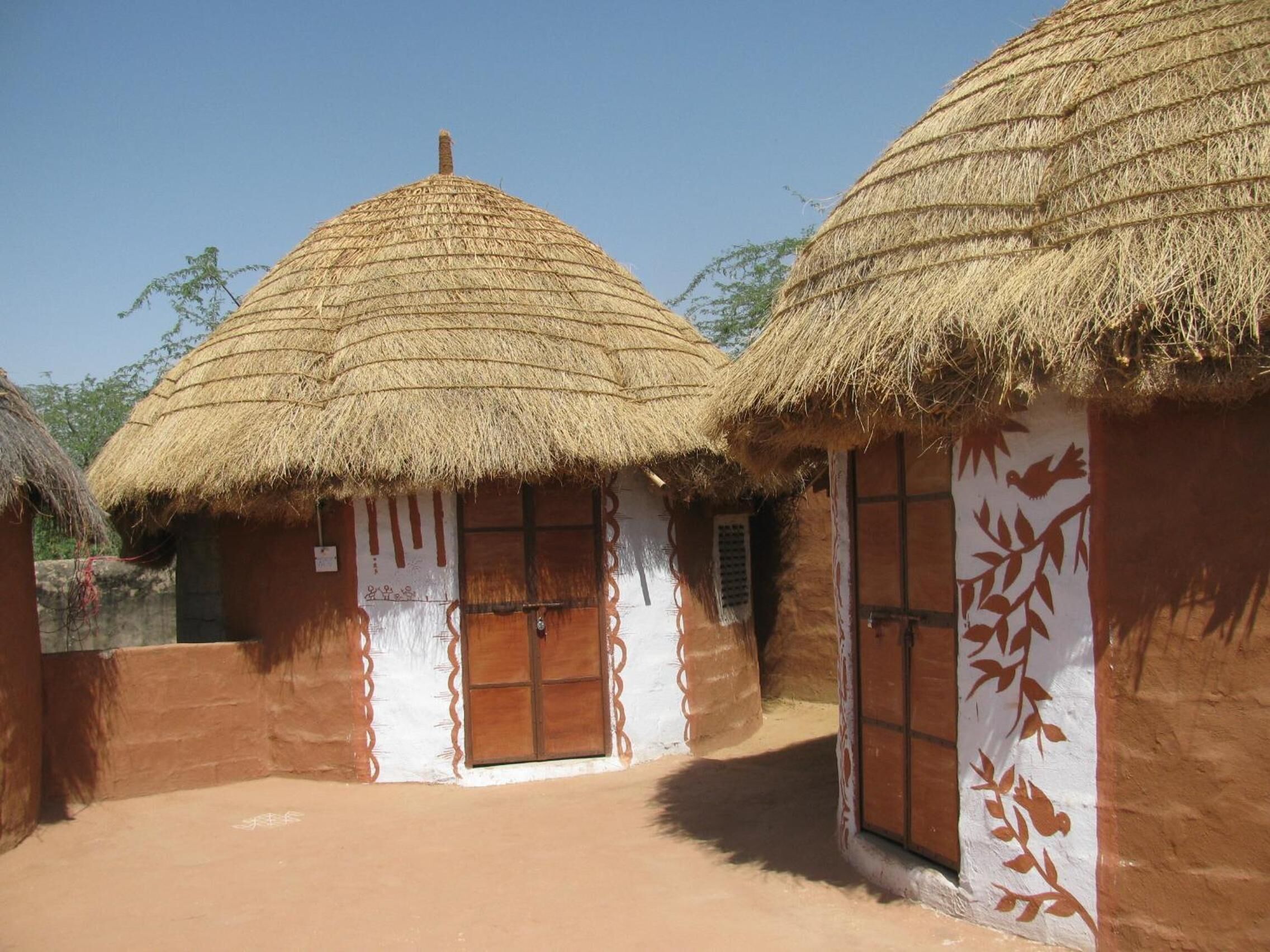 Una cabaña tradicional con techo de paja y un diseño rústico y sencillo, con una puerta central y un pequeño ventanal.