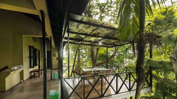 Eine Holzterrasse mit Tisch und Stühlen, umgeben von üppigem Grün.