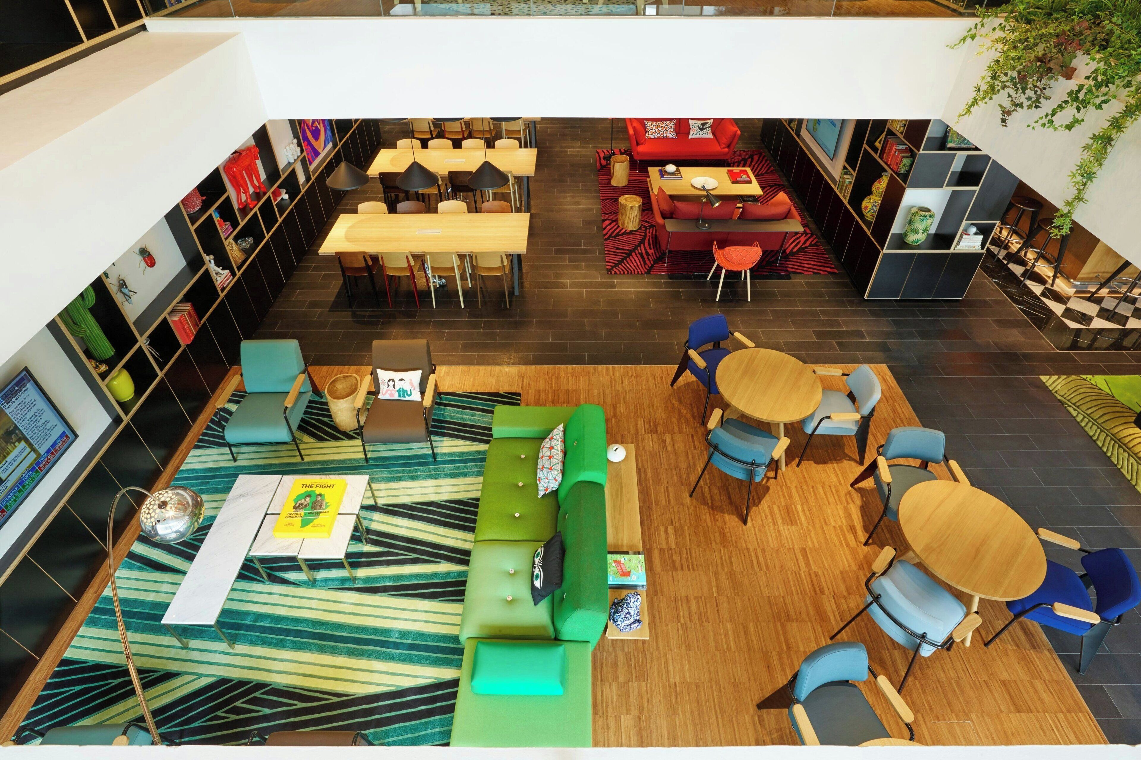 A modern indoor space with a green sofa, wooden tables, and blue chairs.