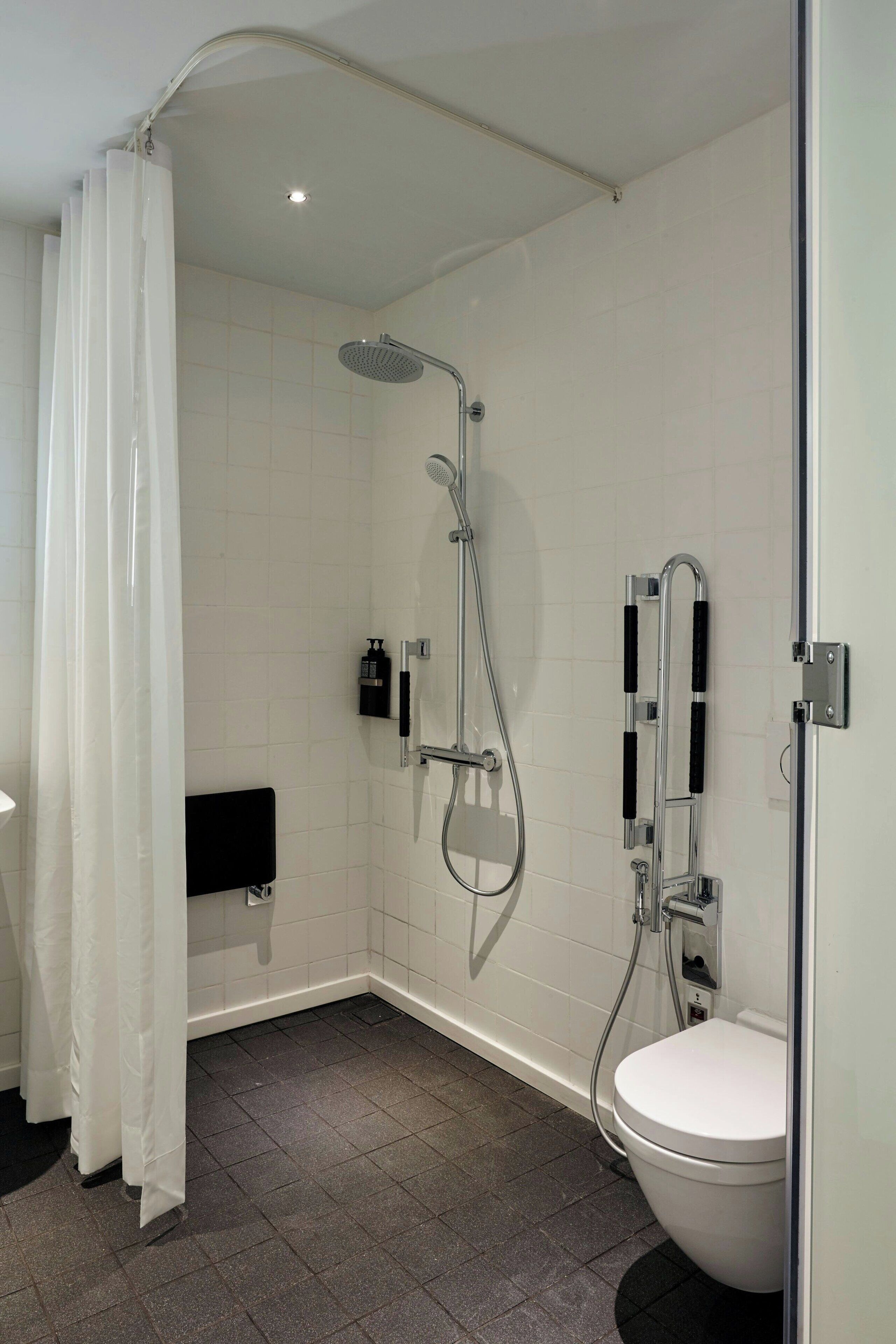 A modern bathroom with a shower, toilet, and a towel rack.