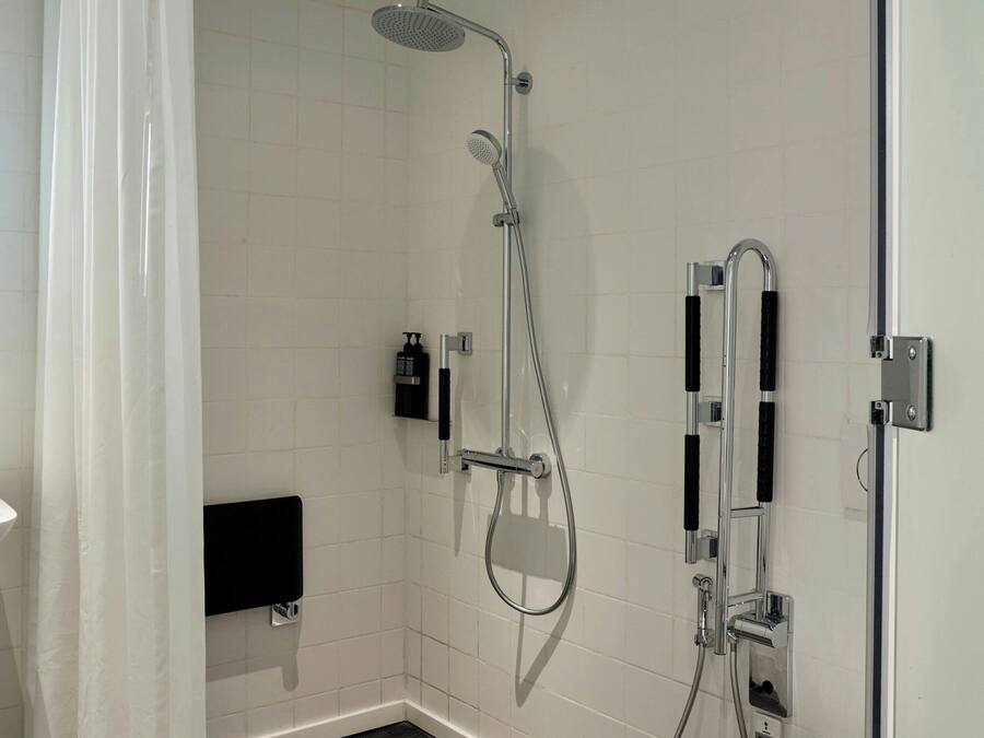 A modern bathroom with a shower, toilet, and a towel rack.