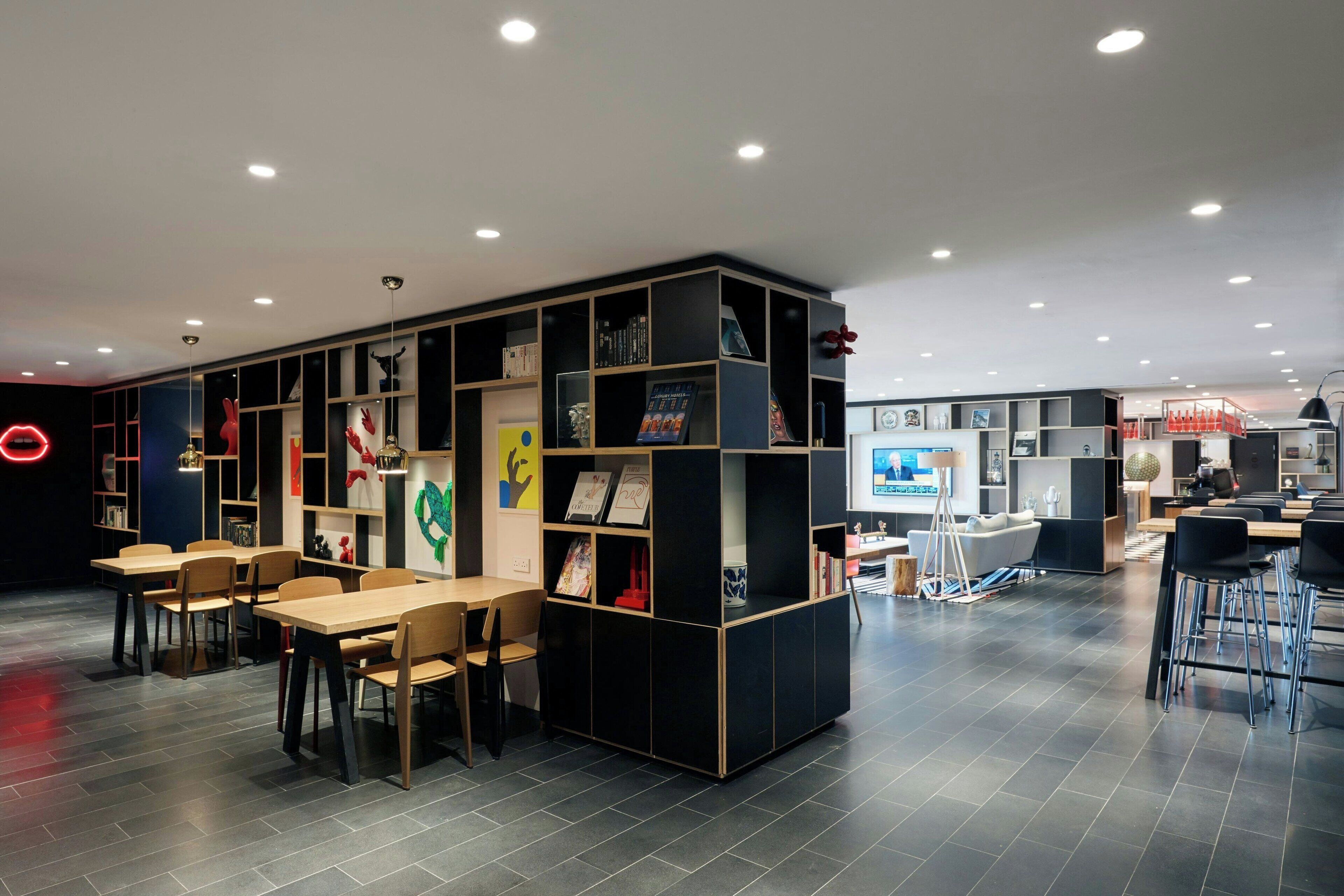 A modern library with bookshelves, tables, and chairs.