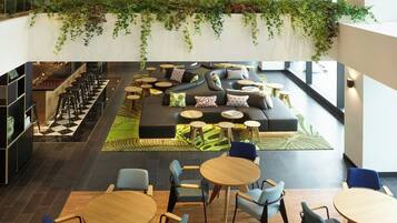 A spacious indoor area with a green sofa, multiple seating arrangements, and a ceiling with a colorful mural.