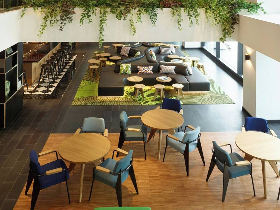 A spacious indoor area with a green sofa, multiple seating arrangements, and a ceiling with a colorful mural.