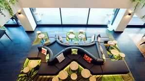 A modern lounge area with a curved sofa, round tables, and a patterned rug.