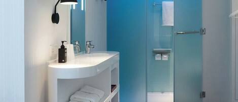A modern bathroom with a white vanity, a glass-enclosed shower, and a blue-lit glass door.