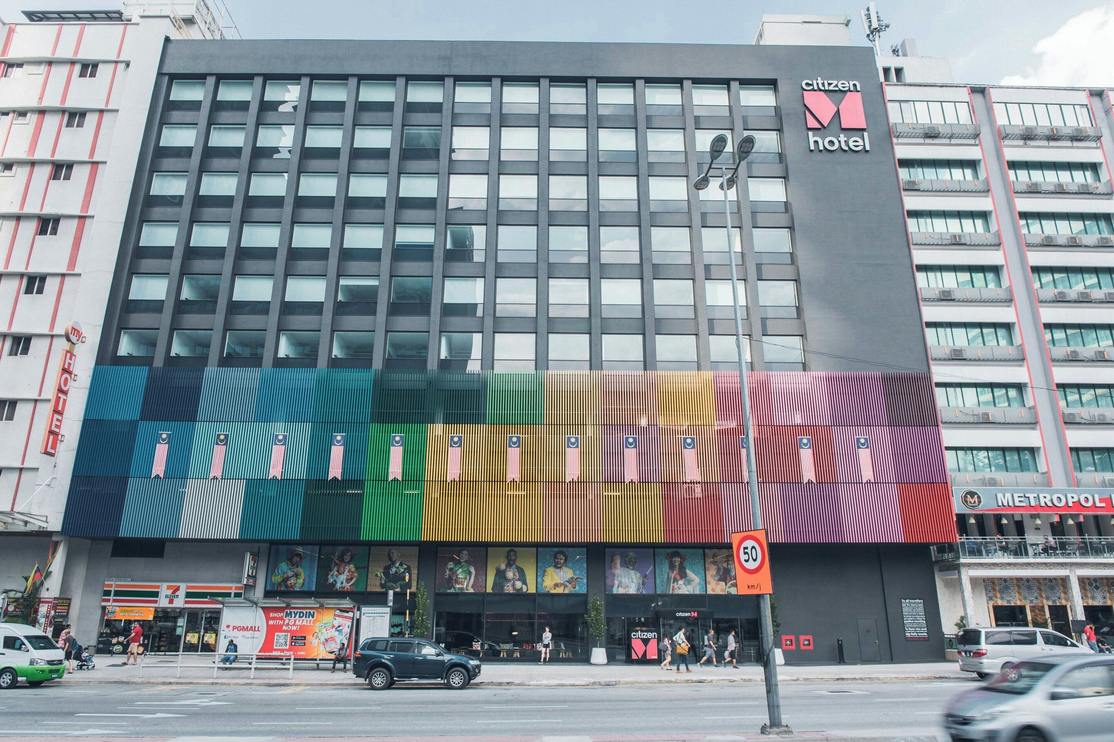 A modern hotel building with a large, colorful advertisement on the facade.