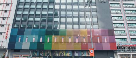 A modern hotel building with a large, colorful advertisement on the facade.