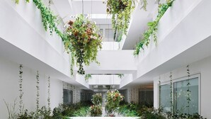 A modern atrium with white walls, multiple levels, and lush greenery.