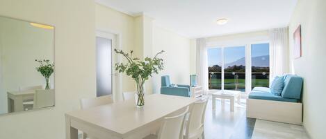 A modern living room with a dining area, large windows, and a view of a mountain.