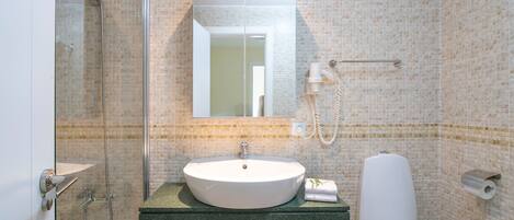Une salle de bain avec une douche à parois de verre, un lavabo avec un miroir au-dessus et des toilettes.