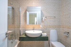 Ein Badezimmer mit einer Duschkabine, einem Waschbecken mit Spiegel darüber und einer Toilette.