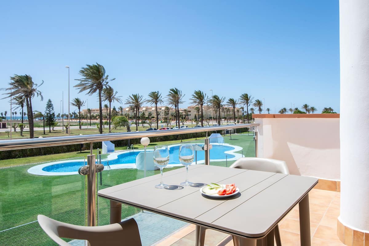 A balcony with a table, two glasses, and a plate of food.