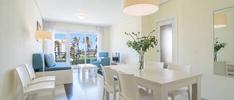 Una sala de estar moderna con comedor, un ventanal con vistas a palmeras y un balcón.