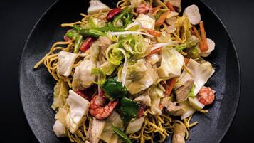Un plato de fideos salteados con verduras y carne.