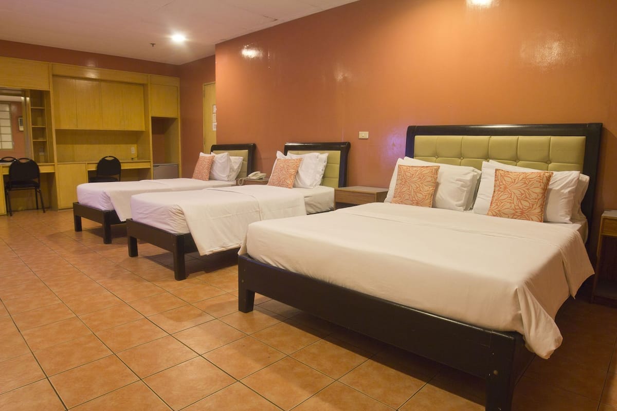A hotel room with two single beds, a desk, and a chair.
