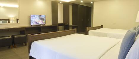 Habitación de hotel con dos camas, televisión, escritorio y espejo.