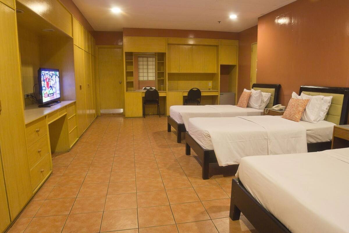 A hotel room with two beds, a desk, a television, and a wardrobe.