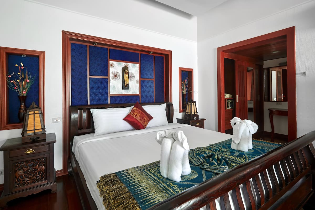 Une chambre d’hôtel avec un grand lit, une tête de lit en bois, une table de chevet avec une lampe et un miroir.