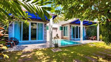 A house with a swimming pool, covered patio, and a garden with chairs and plants.