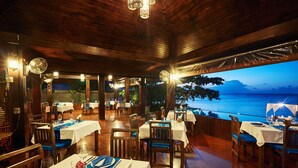 An outdoor dining area with tables set for dinner, overlooking a body of water. - Sea Valley Resort (Koh Samui)