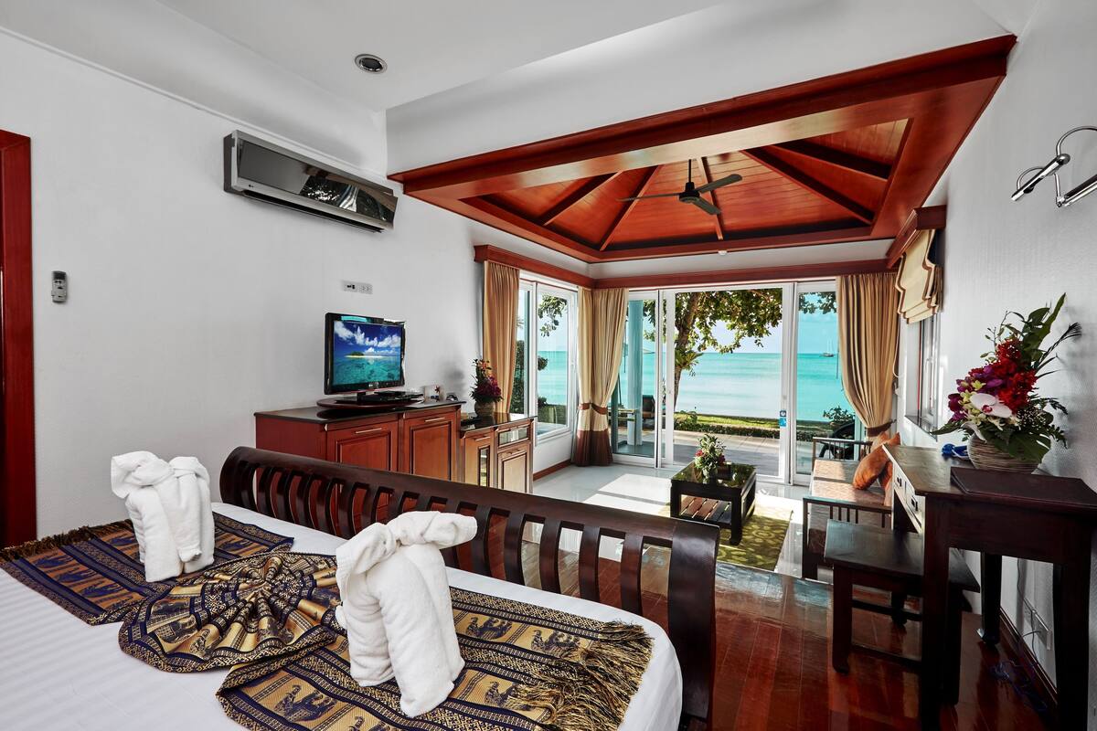 Une chambre d’hôtel avec un lit, un bureau, une télévision et une vue sur l’océan.